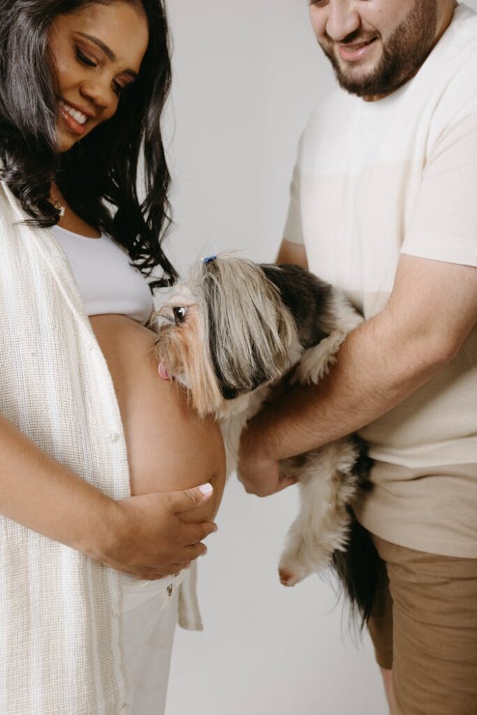 A joyful couple with their dog, celebrating pregnancy in a studio setting.